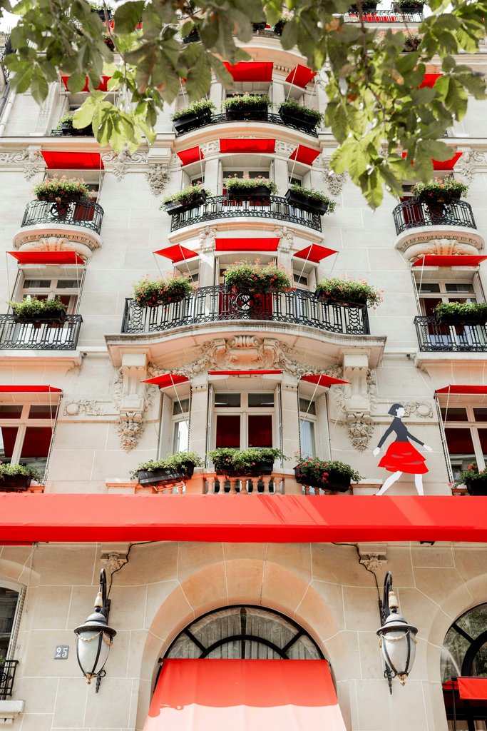 Veronica Lybbert - A tall white building with red awnings and windows photo