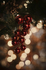 Tim Mossholder - Close-up of red Christmas ornaments on a tree with a warm bokeh background, evoking holiday spirit.