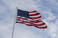 Connor McManus - A vibrant American flag waves against a clear blue sky, symbolizing freedom and patriotism.