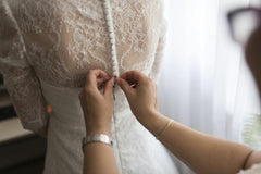 Dmitry Zvolskiy - A bride getting her dress adjusted by a family member indoors, highlighting a touching wedding preparation moment.