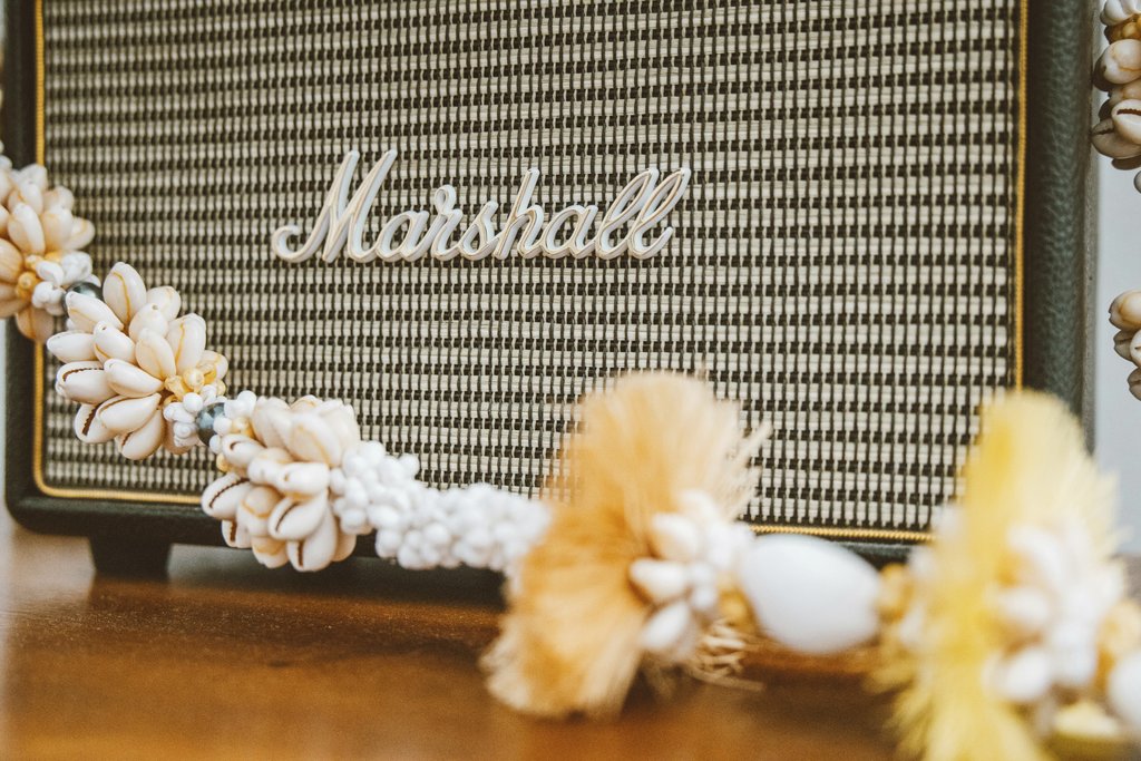 Jess Loiterton - Close-up of a Marshall speaker decorated with a seashell garland, blending music and coastal vibes.