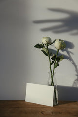 Cup of  Couple - A minimalist mockup featuring white roses in a vase with a blank card on a wooden table; perfect for invitations or messages.