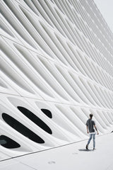 Brady Knoll - Futuristic facade of The Broad museum with a person walking by in daylight.