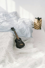 Mikhail Nilov - A tranquil bedroom setting featuring a ukulele on a plush white rug, perfect for relaxation.