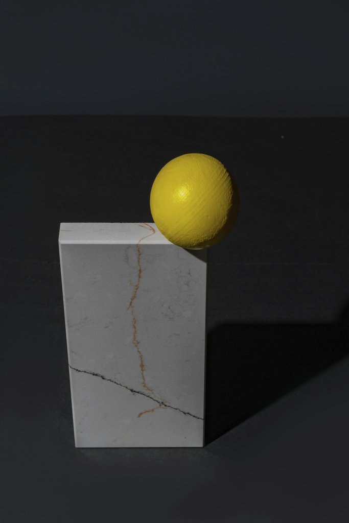 Mikhail Nilov - A striking still life featuring a yellow sphere balanced on a marble cube against a dark backdrop.