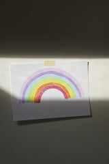 Cup of  Couple - A vibrant hand-drawn rainbow on paper taped to a wall, capturing artistic expression.