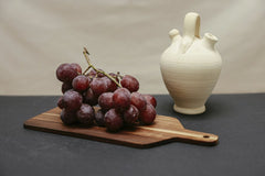 Cup of  Couple - A still life composition featuring red grapes on a wooden board with a ceramic vase.