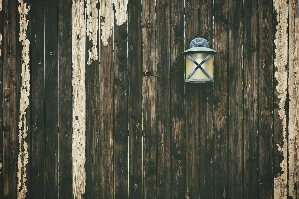 Tim Mossholder - A weathered wooden fence with a vintage lantern adding rustic charm.