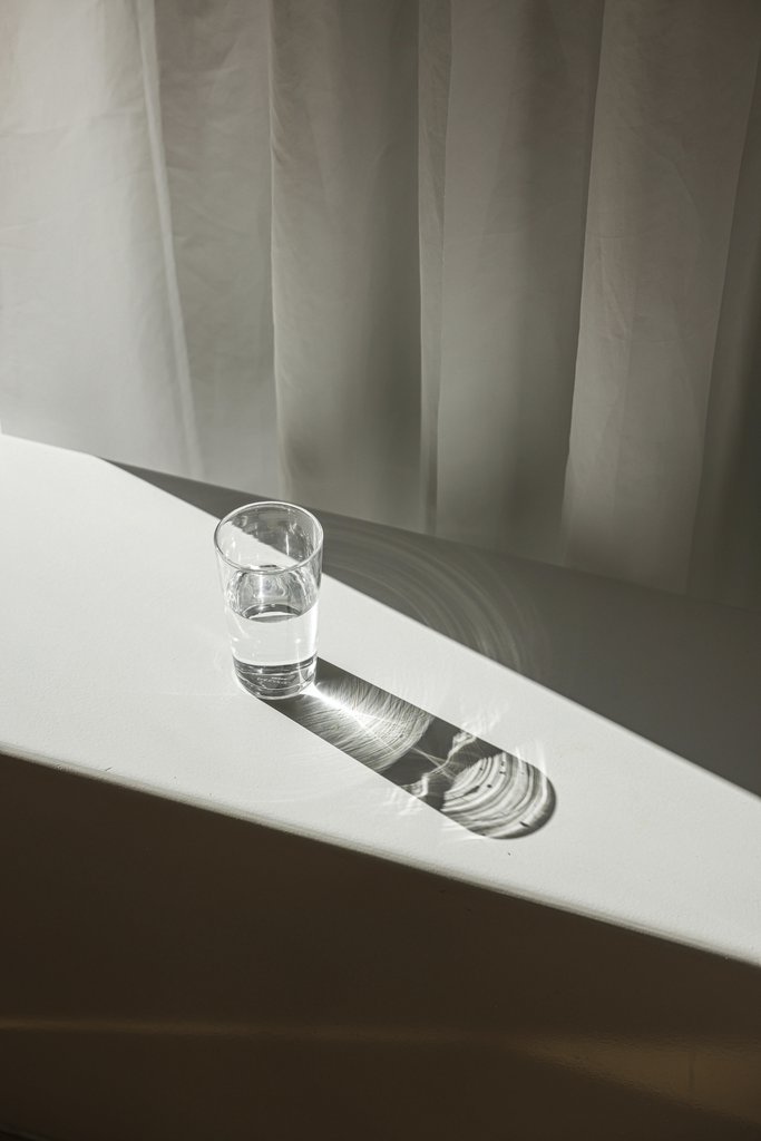 Cup of  Couple - A glass of water on a white table casting dramatic shadows in soft sunlight.