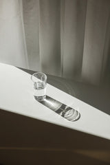 Cup of  Couple - A glass of water on a white table casting dramatic shadows in soft sunlight.