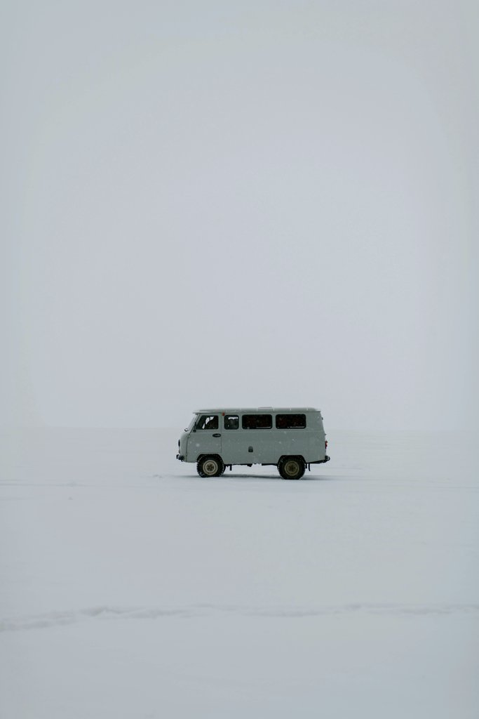 Julia Volk - A solitary van traverses a vast snowy expanse in Russia, capturing winter's stark beauty.