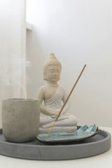 Max Vakhtbovycn - A serene Buddha statue with smoldering incense, symbolizing peace and spirituality in a minimalist setting.