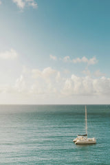 Jess Loiterton - A solitary sailboat floats on a tranquil sea under a bright blue sky.