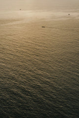 Alesia  Kozik - A tranquil view of the ocean at sunset with small boats in Bali, Indonesia.