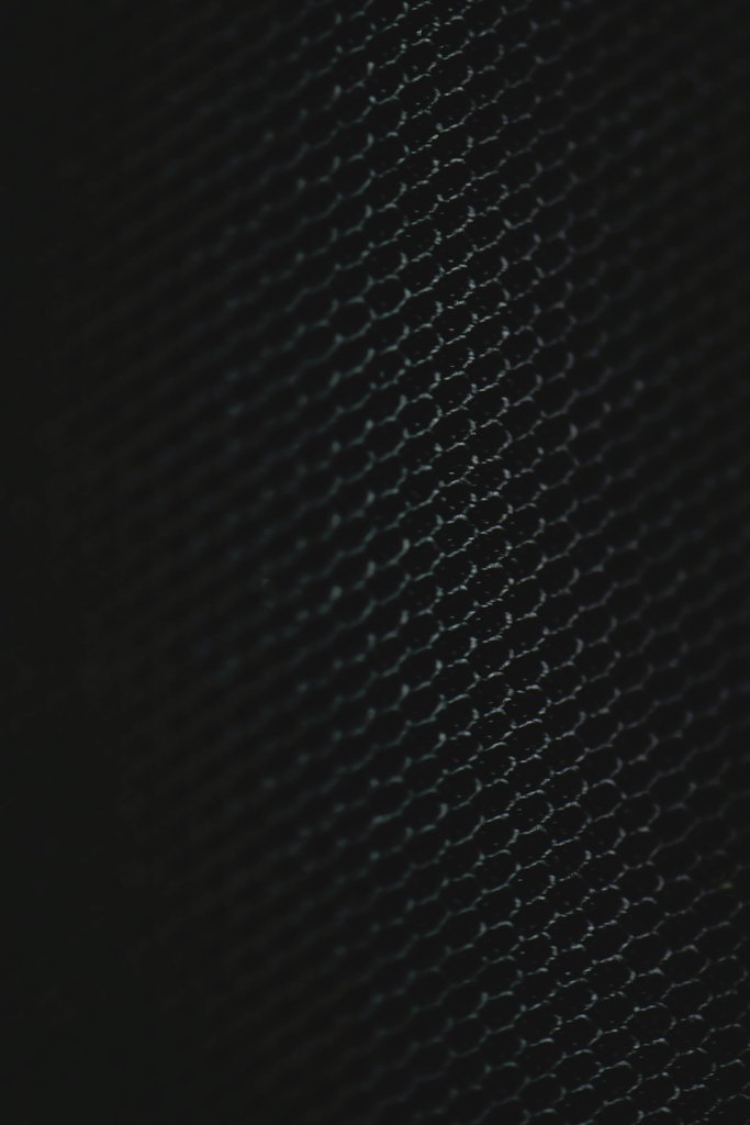 Eva Bronzini - Close-up of a dark patterned surface with a mesh texture in Estonia.