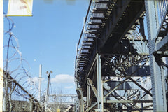 Garrison Gao - Elevated metal bridge structure in an industrial district with clear blue sky.