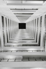 Neevin Alvin ✳️ - Dramatic black and white view of a modern vertical staircase from below.