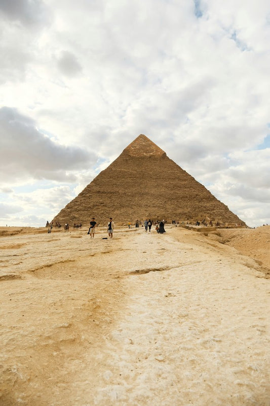 Harun - Tourists visiting the iconic Great Pyramid of Giza, a UNESCO World Heritage site, under a vast cloudy sky.