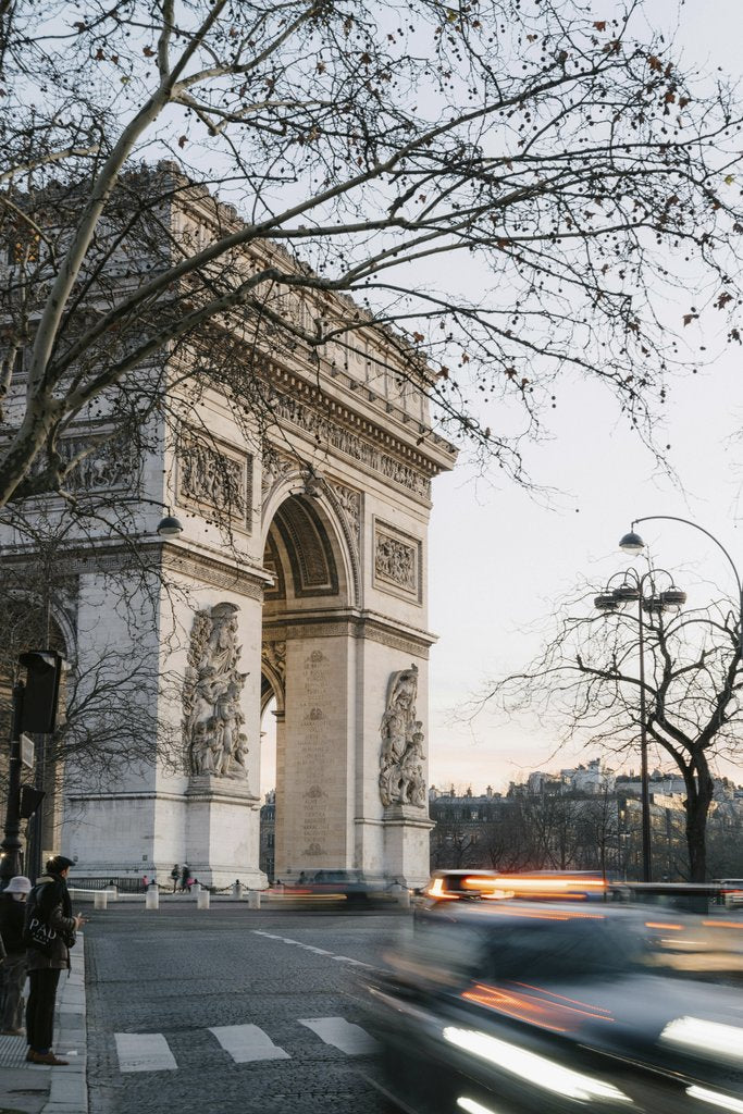 Mathias Reding - View of the Arc de Triomphe in Paris at dusk with blurred car motion and winter trees.