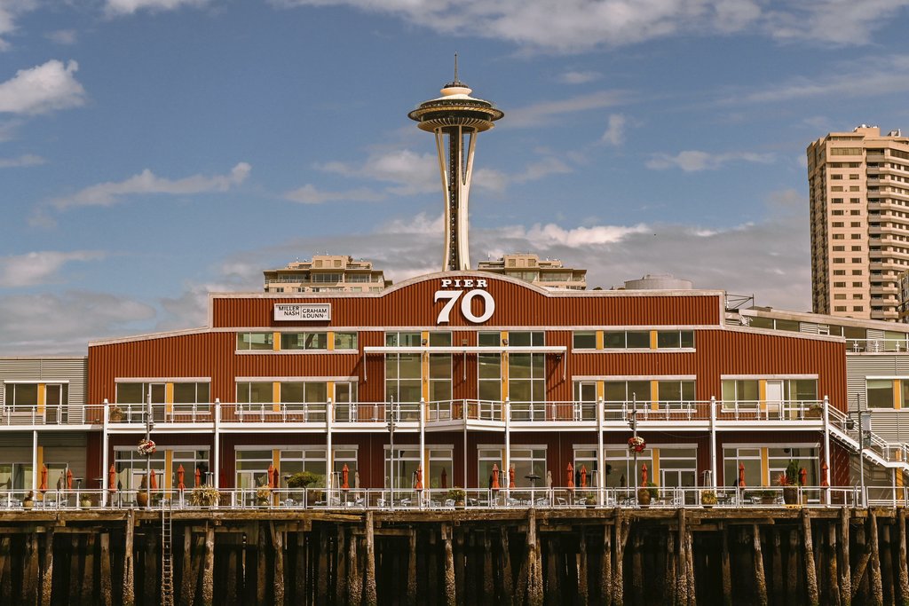 Caio - View of Seattle's iconic Space Needle behind Pier 70 against a clear blue sky.