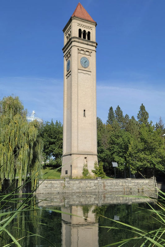 Tom  Shamberger - Iconic clock tower reflecting in a serene Spokane park with blue skies.
