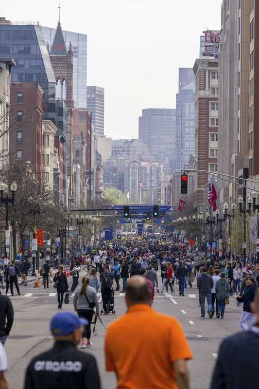 Fatih Turan - A bustling urban street filled with a diverse crowd during a daytime city event, showcasing tall buildings.