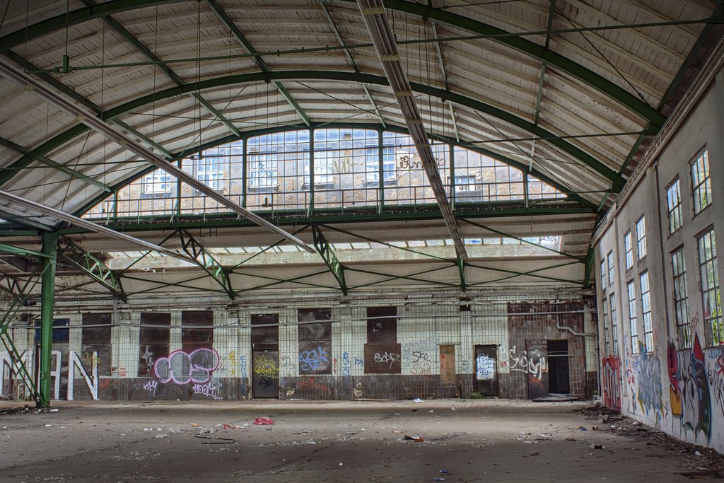 Antonio Friedemann - Interior of an abandoned warehouse with graffiti and debris, showcasing urban decay.