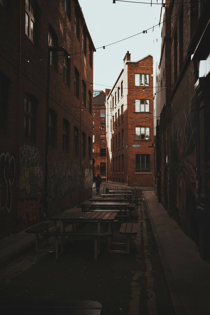 Nathan J Hilton - Discover the charm of a graffiti-lined alley with rustic brick buildings in Manchester, UK.