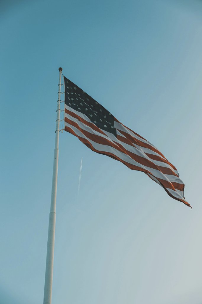 Connor McManus - A striking image of the American flag waving proudly against a clear blue sky, evoking patriotism.