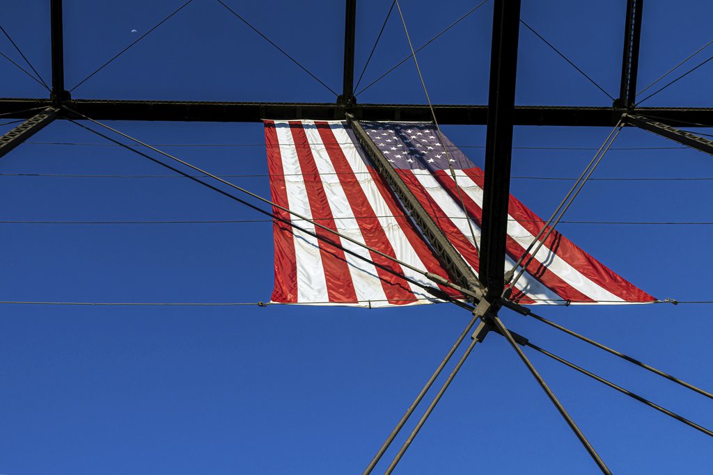 Richard King - American flag displayed on Folsom's historic truss bridge against a clear sky.