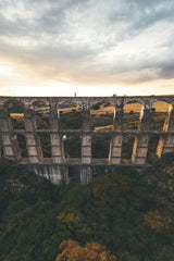 Mikhail Nilov - A breathtaking aerial shot of an ancient aqueduct amidst lush greenery during sunset.