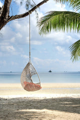 Quang Nguyen Vinh - A peaceful scene with a hanging swing chair on a tropical beach, perfect for relaxation.