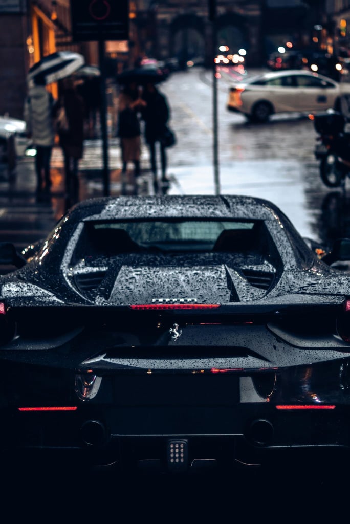 Black Ferrari in the Rainy City, sleek and wet, showcasing luxury car wall art against a rainy urban backdrop.