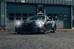 Porsche 911 GT3 RS in Matte Black parked in an industrial setting, showcasing its sleek design and performance features.