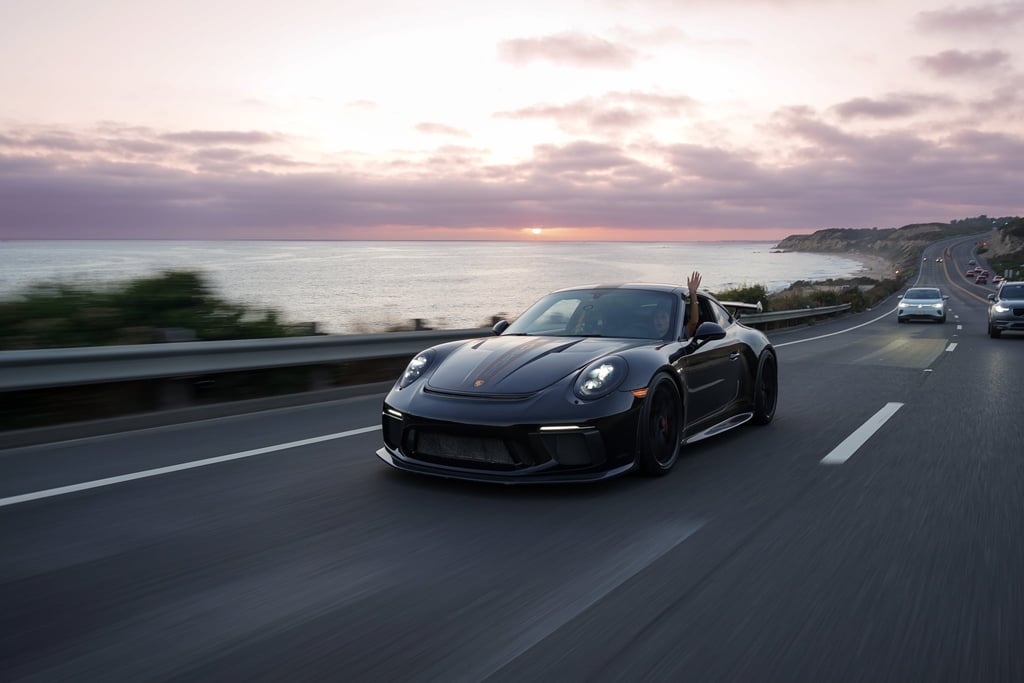 Porsche 911 GT3 Adventure car wall art depicting a black sports car driving along a coastal road at sunset.