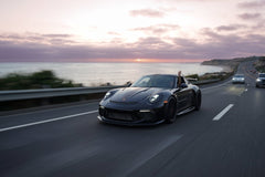 Porsche 911 GT3 Adventure car wall art depicting a black sports car driving along a coastal road at sunset.