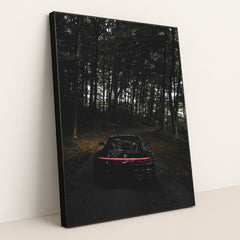This photo shows the rear of a black Porsche with taillights illuminated, parked on a dark forest road, in a black frame.