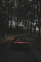Porsche 911 Taillight Glow in the Woods - rear view of a sleek black car in a dark forest with glowing LED taillights.