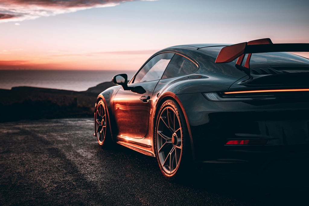 Golden Coast Porsche 911 GT3 parked by the shore at sunset, showcasing sleek design and car wall art aesthetic.