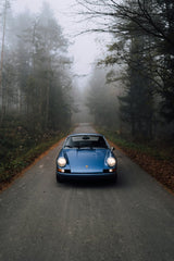 Porsche 911 in a Foggy Daydream, blue car wall art on a foggy road surrounded by trees.