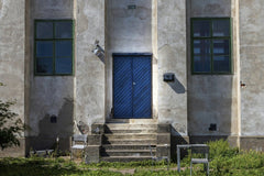 Laura Lumimaa - Explore the rustic charm of an abandoned building facade featuring a bold blue door in Helsinki, Finland.