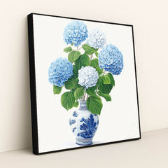 This artwork features a bouquet of blue and white hydrangeas in a blue and white porcelain vase, in a black frame.