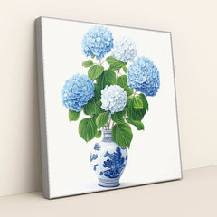 This artwork features a bouquet of blue and white hydrangeas in a blue and white porcelain vase, in a silver frame.