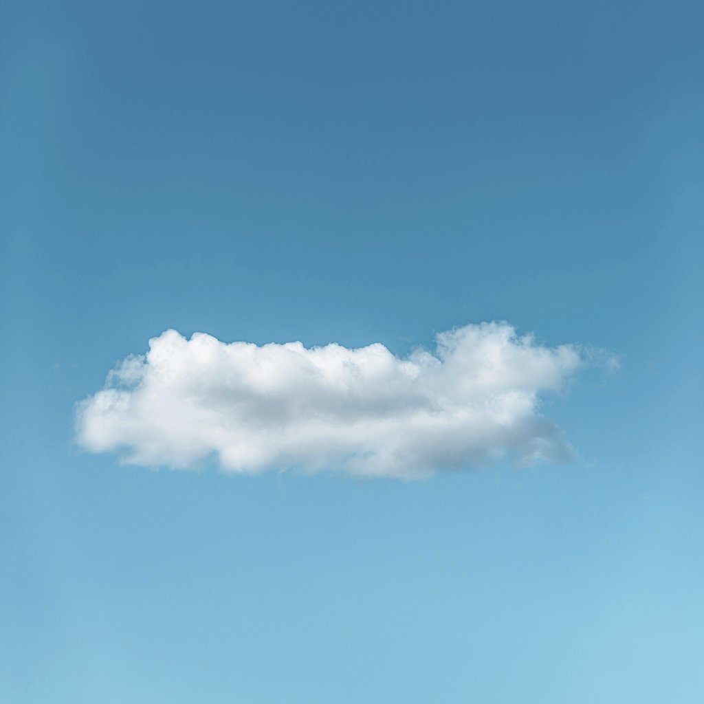 Stanislav Kondratiev - A lone fluffy cloud set against a bright blue sky, showcasing serene simplicity.