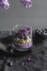 Anna Pyshniuk - A stylish vertical shot of a blueberry granola parfait with lilac flowers.