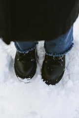 Kino - A pair of black winter boots standing in snow, showcasing snowy terrain and winter fashion.