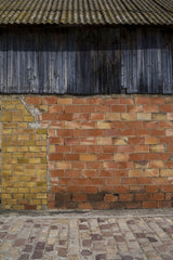 Victor  Moragriega - Close-up of a textured exterior wall with wooden and brick sections showcasing diverse colors and materials.