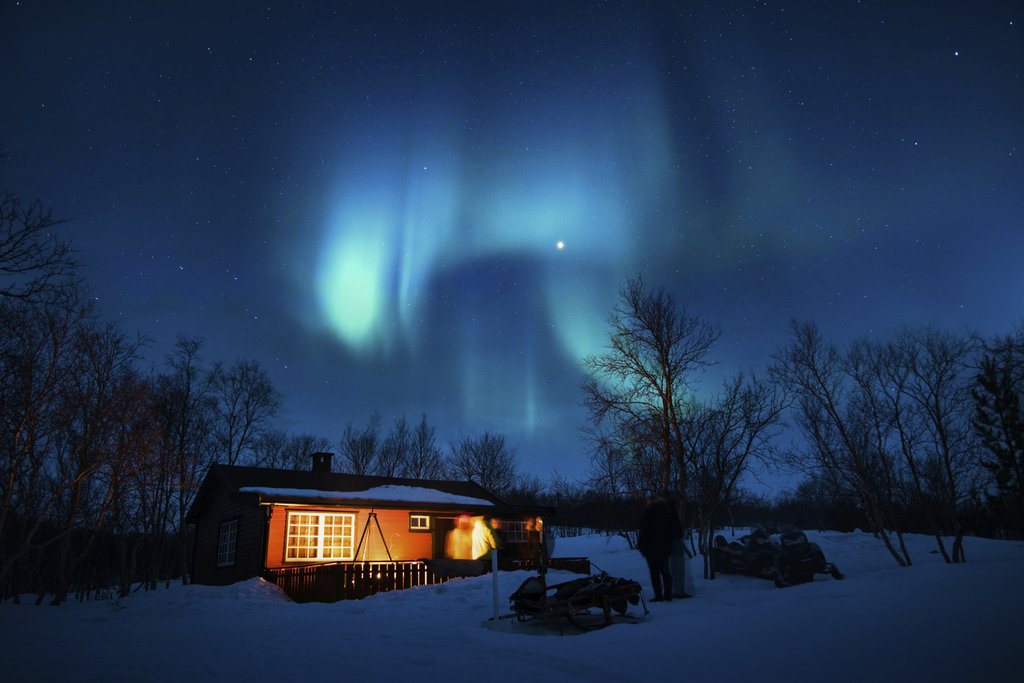Stefan Stefancik - Cabin illuminated under a stunning aurora borealis and starry winter night sky.