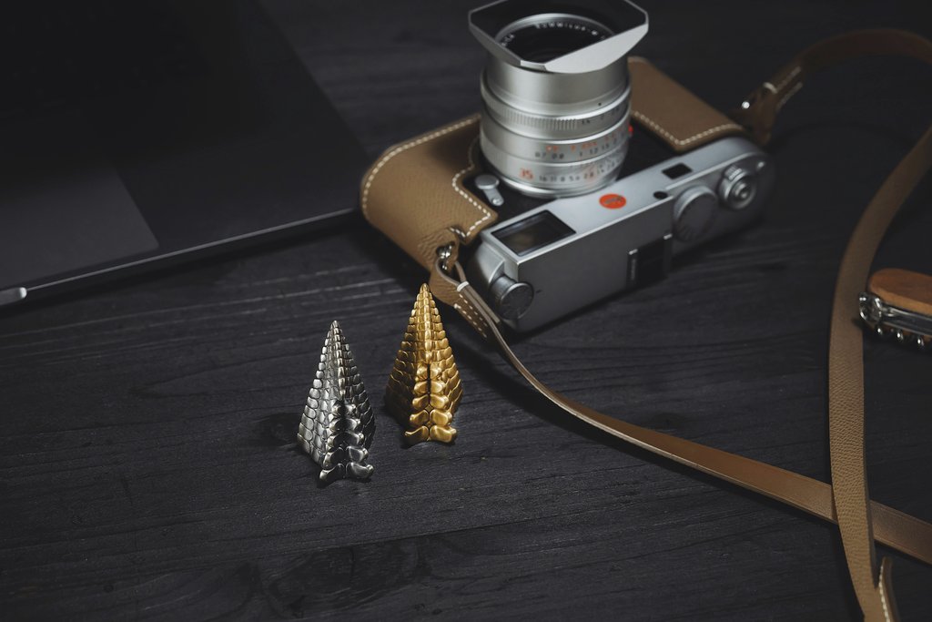 COPPERTIST WU - A vintage camera and stylish metal tree sculptures on a dark wooden table.