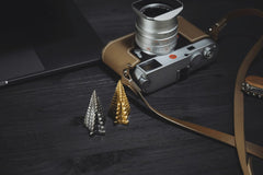 COPPERTIST WU - A vintage camera and stylish metal tree sculptures on a dark wooden table.